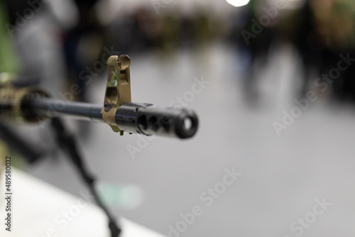 The muzzle with the sight of an army assault rifle is pointed at the camera. Close-up of the weapons, background blurred., Copyspace