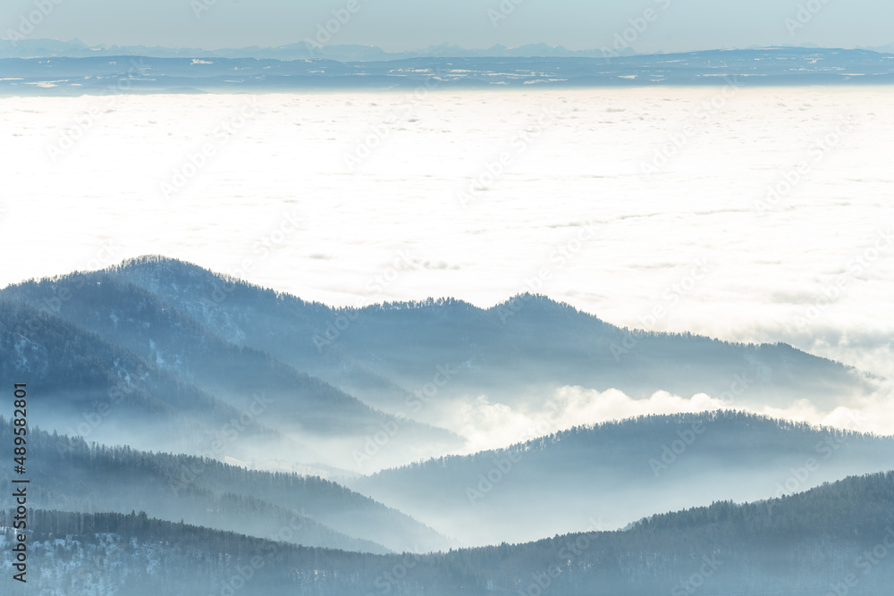 Silhouette of mountains in the mist above the sea of fog in winter.