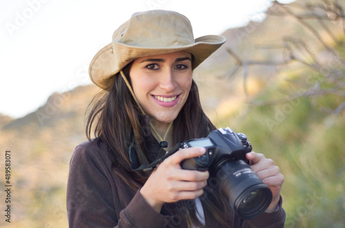 She takes her camera wherever she goes. Portrait of a beautiful young hiker. © Antonio D/peopleimages.com