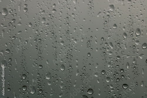 Rain drops on a window with a stormy sky background. Focus is on the drops. A wintery image.
