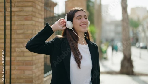 Young hispanic girl smiling confident listening to music and dancing at street