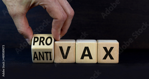 Pro-vax or anti-vax Covid-19 symbol. Doctor turns cubes, changes words Anti-vax to Pro-vax. Beautiful grey table, grey background. Copy space. Business, medical covid-19 pro-vax or anti-vax concept. photo