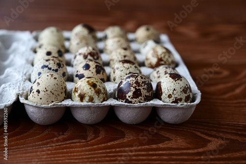 quail eggs in cardboard packaging on a wooden background. The idea of healthy breakfast, symbol of Easter.. Copy space