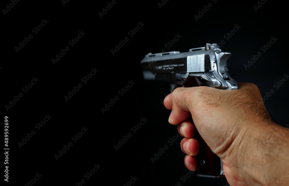 Male hand holding a gun on black background . A gun in a man's hand. defense or attack murderer or armed robber, First person view of a pistol. Male hand holding a gun on black background . A gun in a man's hand. defense or attack murderer or armed robber, First person view of a pistol.