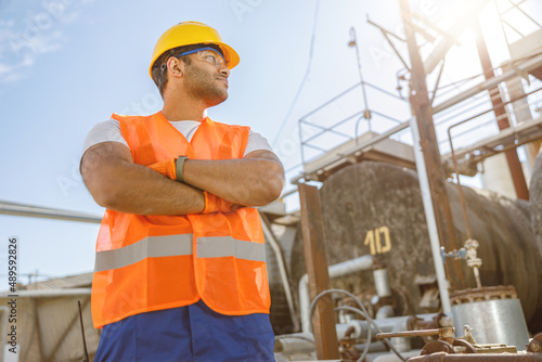 Confident young worker standing at industrial site