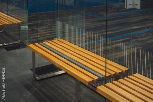 close-up photo of a wooden bench near the entrance to a tennis court