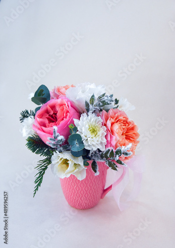 bouquet of luxurious roses in a pastel ceramic cup on a light background with a natural soft shadow. Small bouquet. morning surprise. view from above 