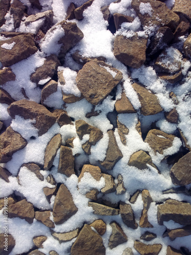 The texture of large stones with snow. Background of cobblestones.
