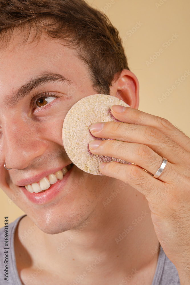 custom made wallpaper toronto digitalYoung and happy man taking care of his skin. Skin care routine. Beautiful model and spa. Isolated beige background.