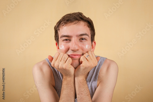 Wallpaper Mural Young and happy man taking care of his skin. Skin care routine. Beautiful model and spa. Isolated beige background. Torontodigital.ca