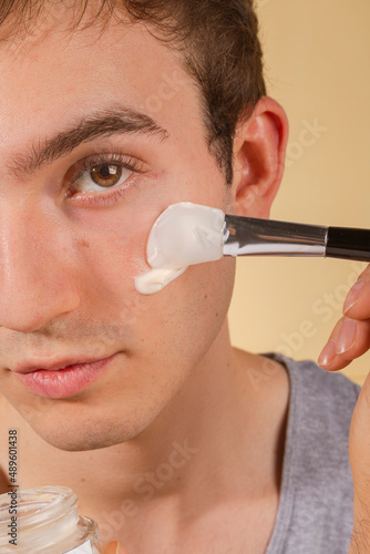 Wallpaper Mural Young and happy man taking care of his skin. Skin care routine. Beautiful model and spa. Isolated beige background. Torontodigital.ca
