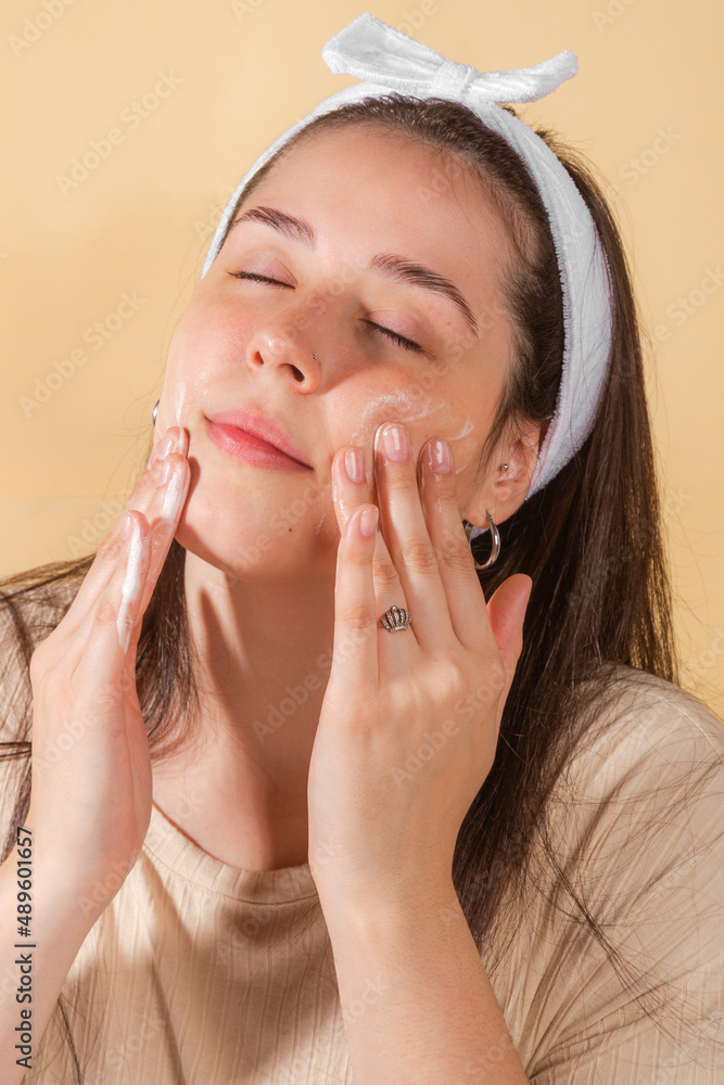 custom made wallpaper toronto digitalportrait young woman uses creams of her face. Isolated on a beige background. Happy healthy model skin care routine