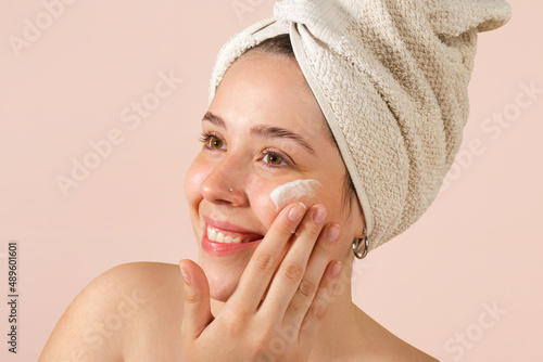 Wallpaper Mural portrait young woman uses creams of her face. Isolated on a beige background. Happy healthy model skin care routine Torontodigital.ca