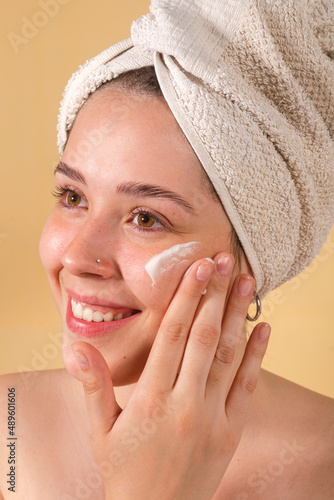 Wallpaper Mural portrait young woman uses creams of her face. Isolated on a beige background. Happy healthy model skin care routine Torontodigital.ca