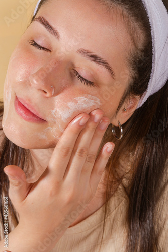 Wallpaper Mural portrait young woman uses creams of her face. Isolated on a beige background. Happy healthy model skin care routine Torontodigital.ca