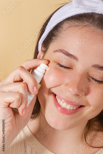 Wallpaper Mural portrait young woman uses creams of her face. Isolated on a beige background. Happy healthy model skin care routine Torontodigital.ca