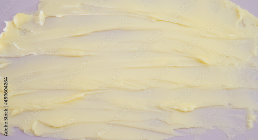 Cosmetic products creamy yellow stain texture on pink background. Texture of natural cosmetics, hair mask, cream, scrub