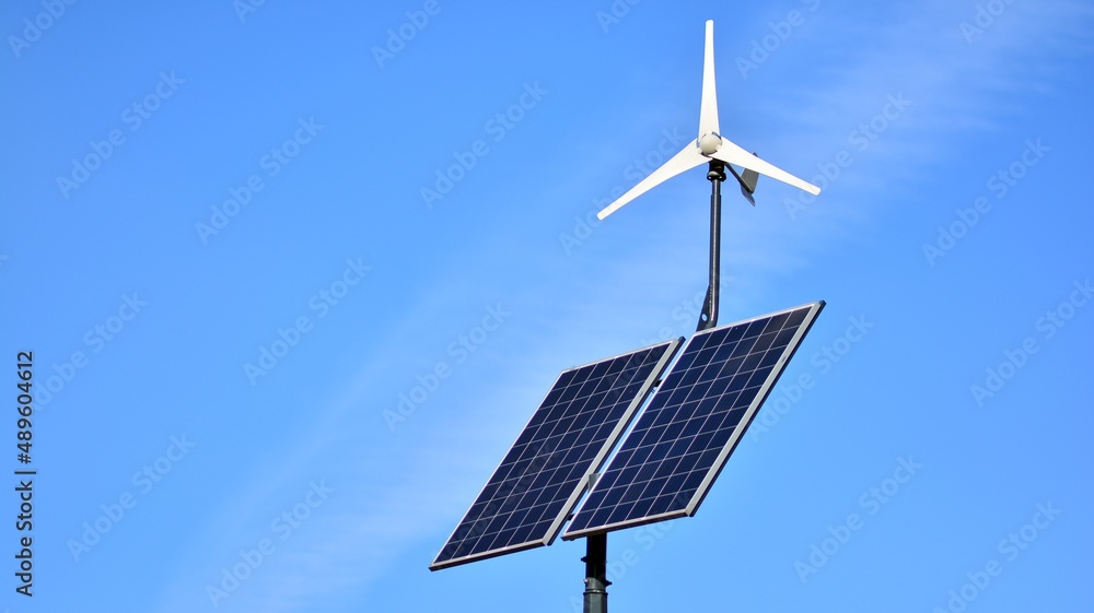 Obraz premium Solar panel and wind turbine against blue sky