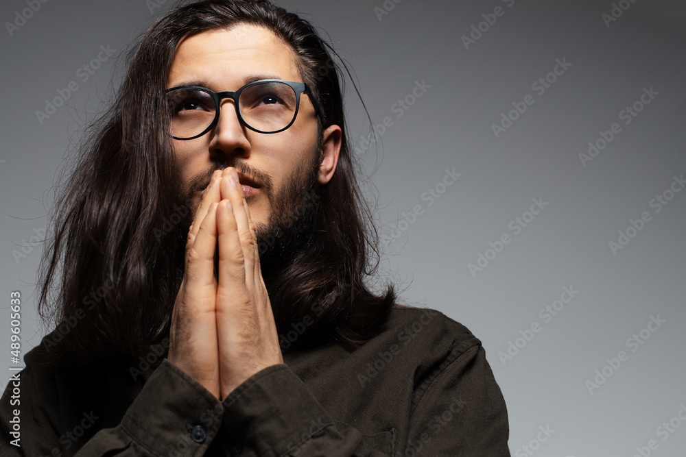 Portrait of handsome man with long hair, holding hands in praying gesture. Portrait of handsome man with long hair, holding hands in praying gesture.