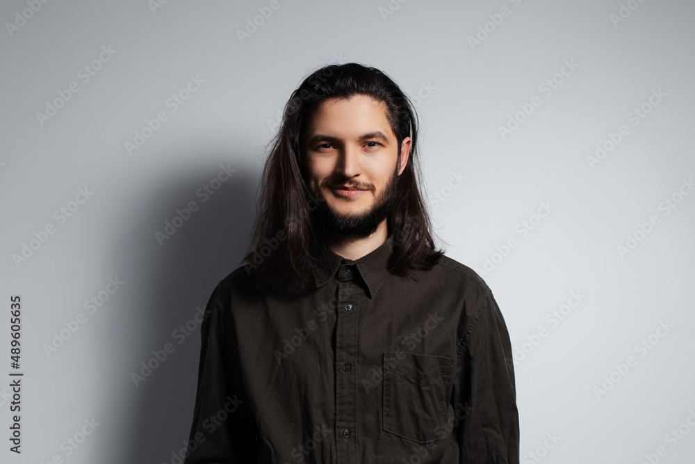 Studio portrait of young handsome man with long hair, on the grey background. Studio portrait of young handsome man with long hair, on the grey background.