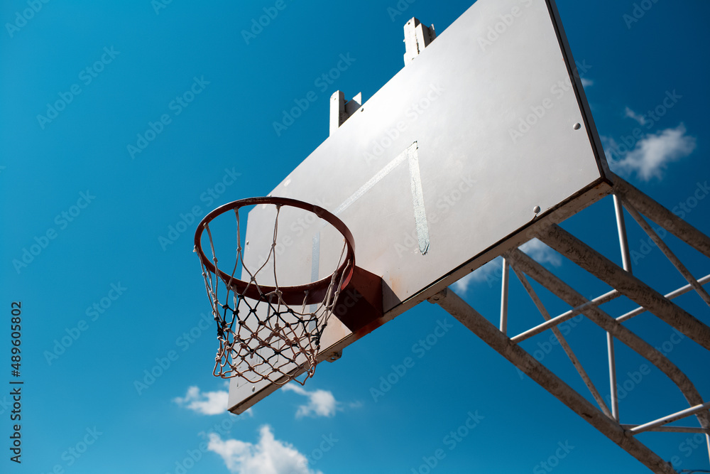 Basketball hoop in sunny day of autumn on background of blue sky.