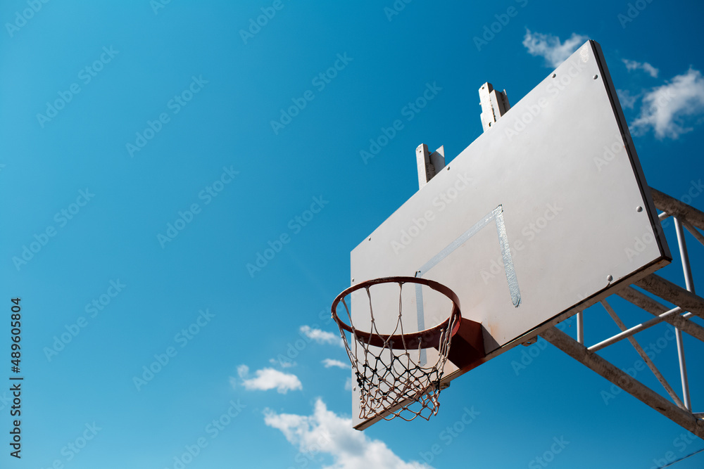 Basketball hoop in sunny day in background of blue sky. Copy space.