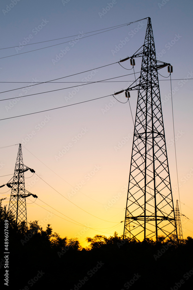 High-voltage power lines at sunset, high voltage electric transmission towers.