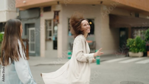 Mother and daughter smiling confident dancing at street