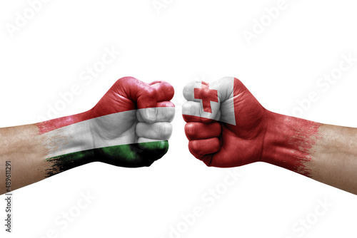 Two hands punch to each others on white background. Country flags painted fists, conflict crisis concept between hungary and tonga