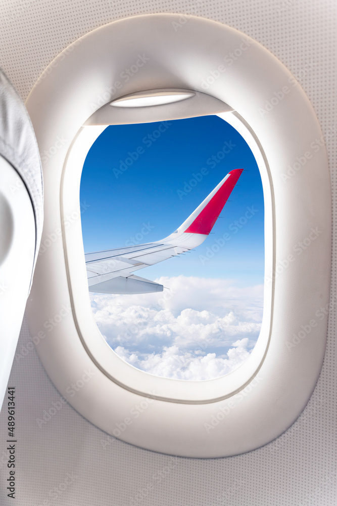 view of white clouds in the sky from the window of an airplane over the wing. view of white clouds in the sky from the window of an airplane over the wing.