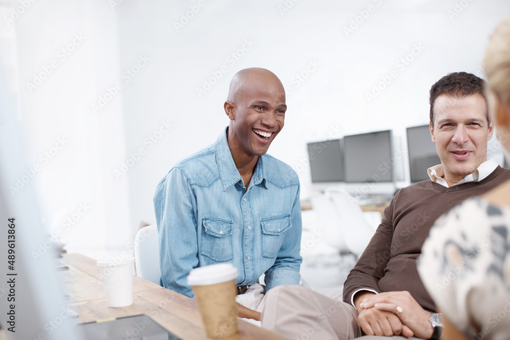 Fototapeta premium Office laughs. Three coworkers talking in an informal meeting together.