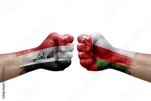 Two hands punch to each others on white background. Country flags painted fists, conflict crisis concept between iraq and oman photo