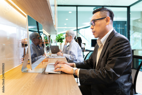Asian businessman in formal suit working in modern luxury coworking space office using computer for business usage