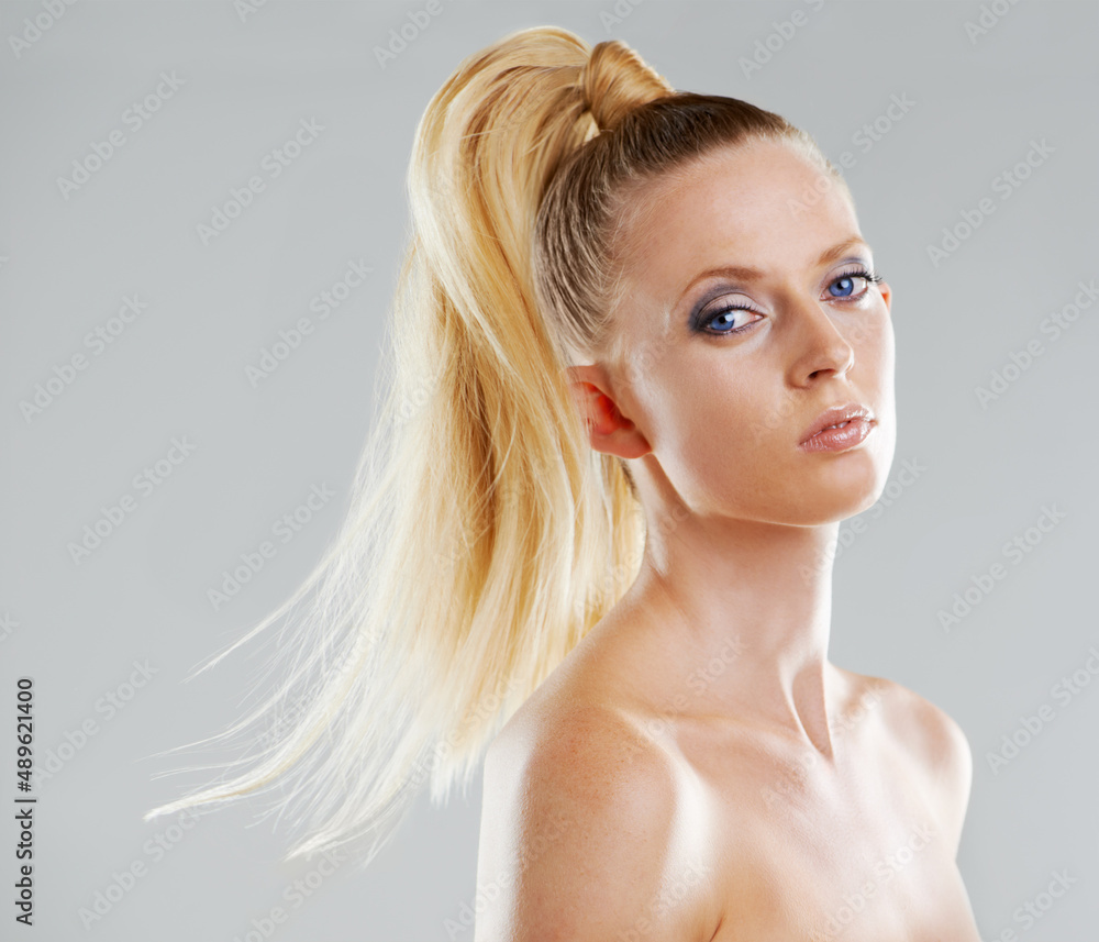 Naturally gorgeous. Portrait of a beautiful young woman with a ponytail against a gray background. Naturally gorgeous. Portrait of a beautiful young woman with a ponytail against a gray background.