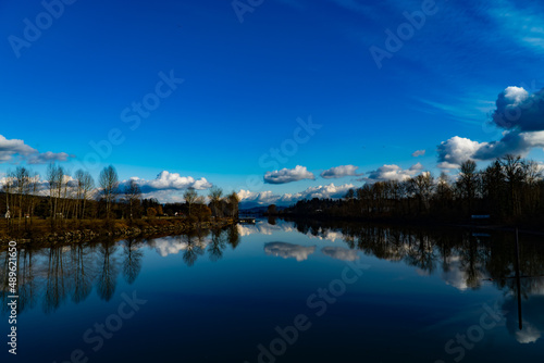 reflection of trees, blue sky and clouds in water