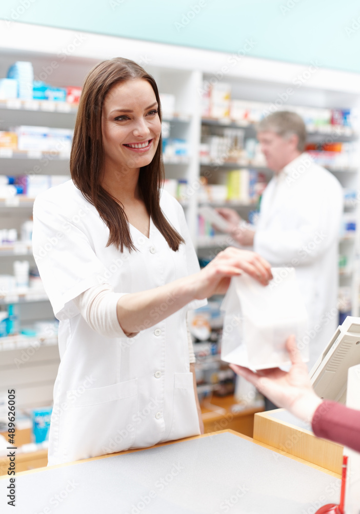 Pharmacist giving package to customer. Portrait of pharmacist handing over the package to customer at medical store.