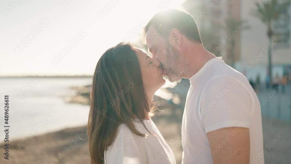 Man and woman couple standing together and kissing at seaside Man and woman couple standing together and kissing at seaside