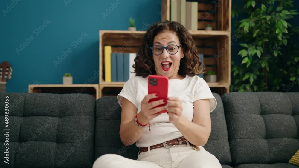 Middle age woman using smartphone with winner expression at home Middle age woman using smartphone with winner expression at home