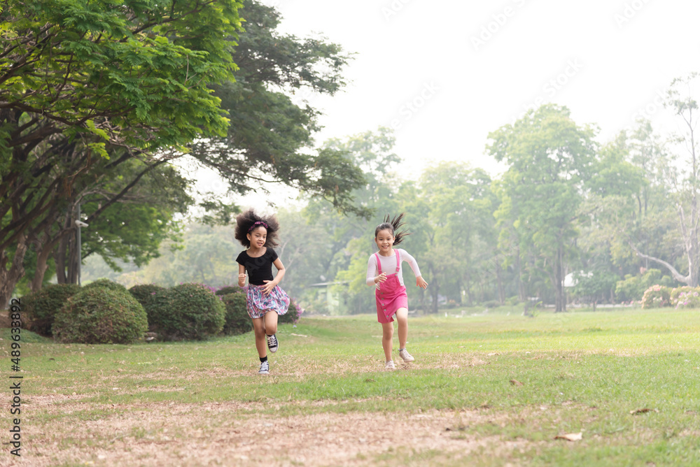Small group of a happy children run through the park in the background of grass and trees. Children's outdoor games, vacations, weekend, Children's Day