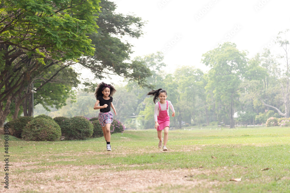 Small group of a happy children run through the park in the background of grass and trees. Children's outdoor games, vacations, weekend, Children's Day