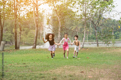 Small group of a happy children run through the park in the background of grass and trees. Children's outdoor games, vacations, weekend, Children's Day