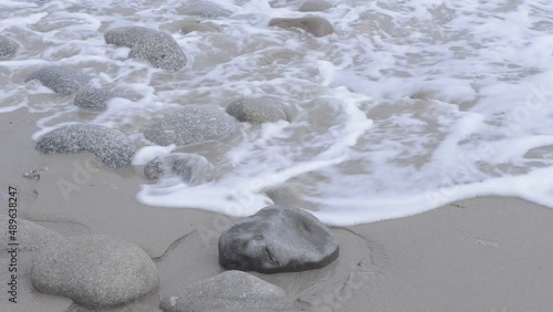 Soft waves lapping the beach sand and rocks