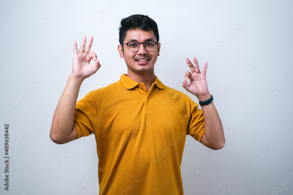 Adult Asian man showing excited face expression while giving two OK finger sign Adult Asian man showing excited face expression while giving two OK finger sign