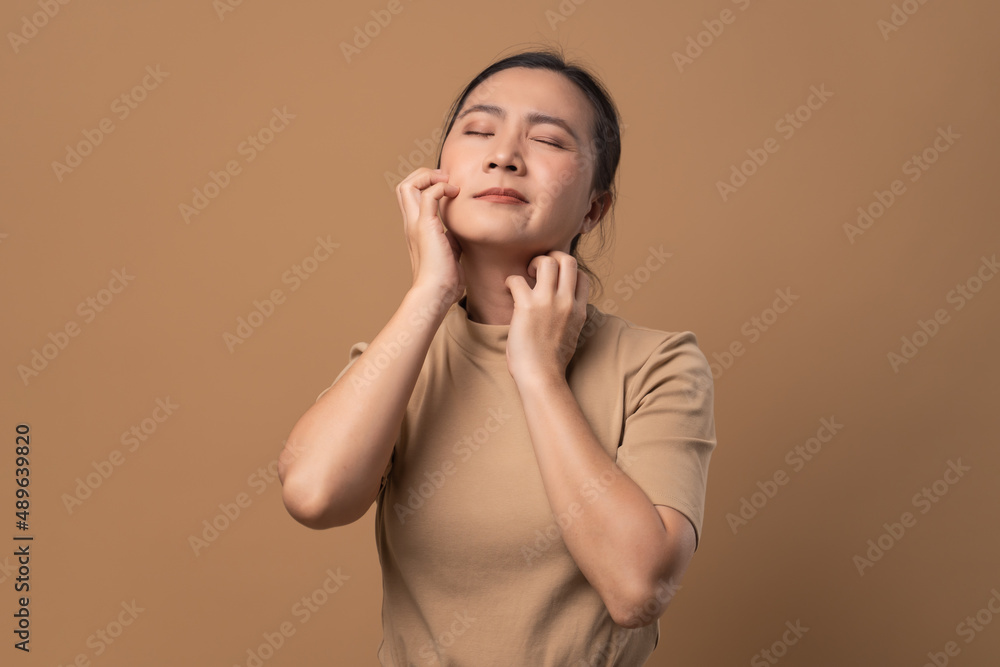 Asian woman was sick with irritate itching her skin standing isolated on beige background. Asian woman was sick with irritate itching her skin standing isolated on beige background.
