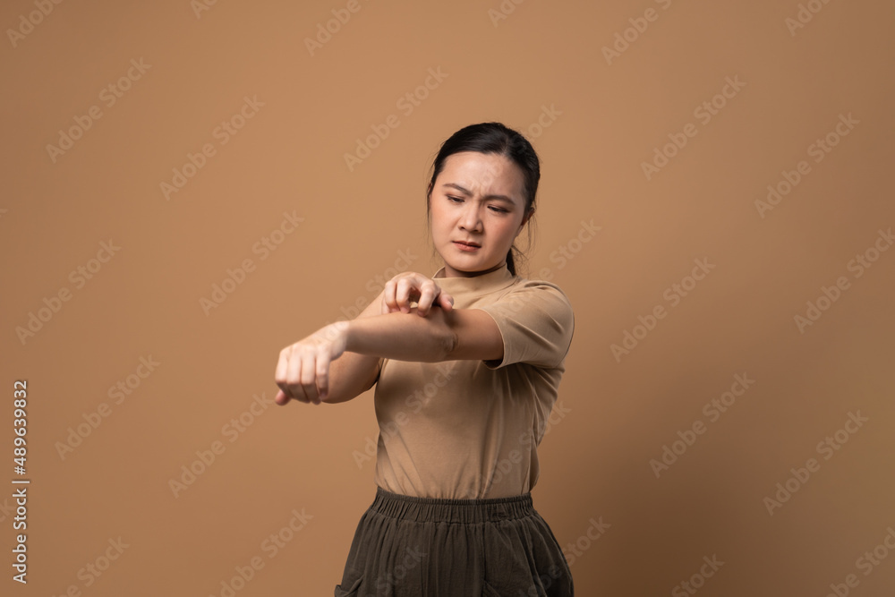 Asian woman was sick with irritate itching her skin standing isolated on beige background. Asian woman was sick with irritate itching her skin standing isolated on beige background.