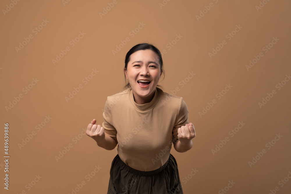 Asian woman happy make a winning gesture isolated on beige background. Asian woman happy make a winning gesture isolated on beige background.