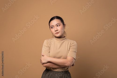 Asian woman feel confuse, standing isolated on beige background.