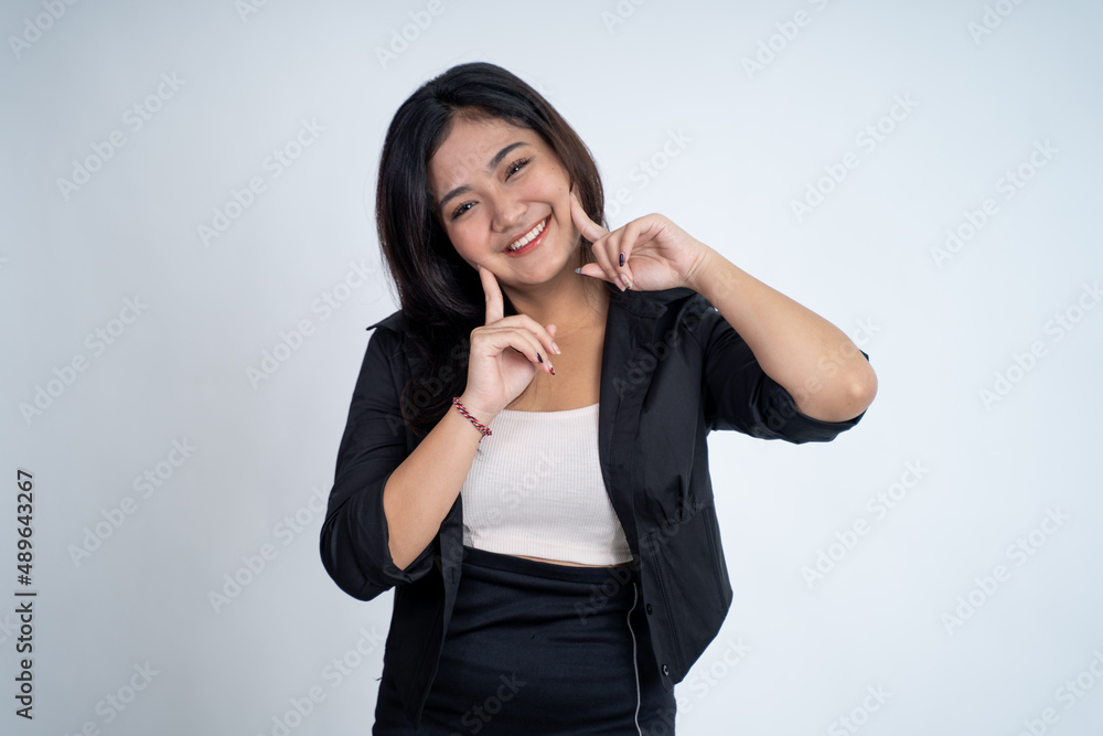 Smiling cute young woman with two fingers pointing to cheek Smiling cute young woman with two fingers pointing to cheek
