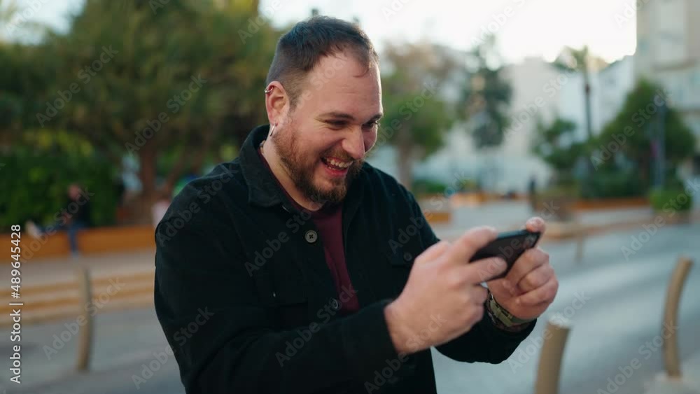 Young plus size man playing video game at park Young plus size man playing video game at park