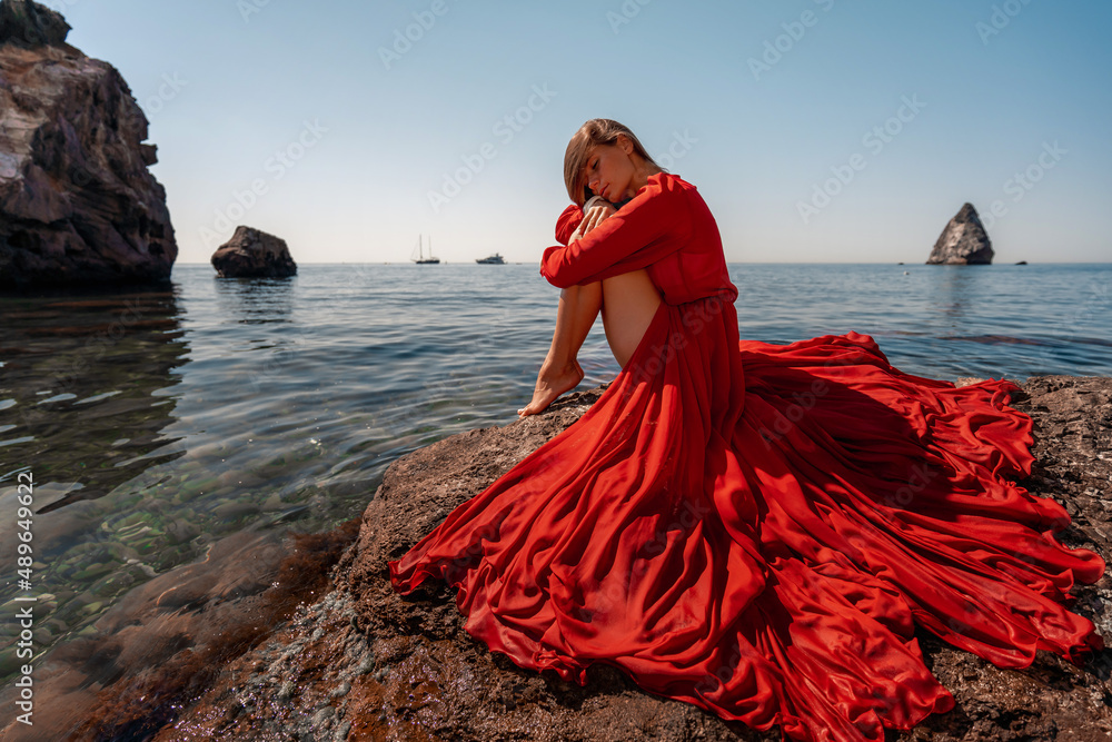 Foto de Beautiful sensual woman in a flying red dress and long hair ...